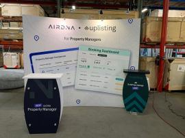 RENTAL: RE-1073 Symphony Inline Design with Large Concave Curved Frame, RE-1255 Backwall Workstation Counter with Two Wireless Charging Ports, (2) LED Arm Lights, SEG Fabric Graphics, and Vinyl Applied Graphic